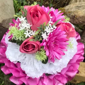 A graveside funeral posy of artificial silk flowers in shades of pink & white